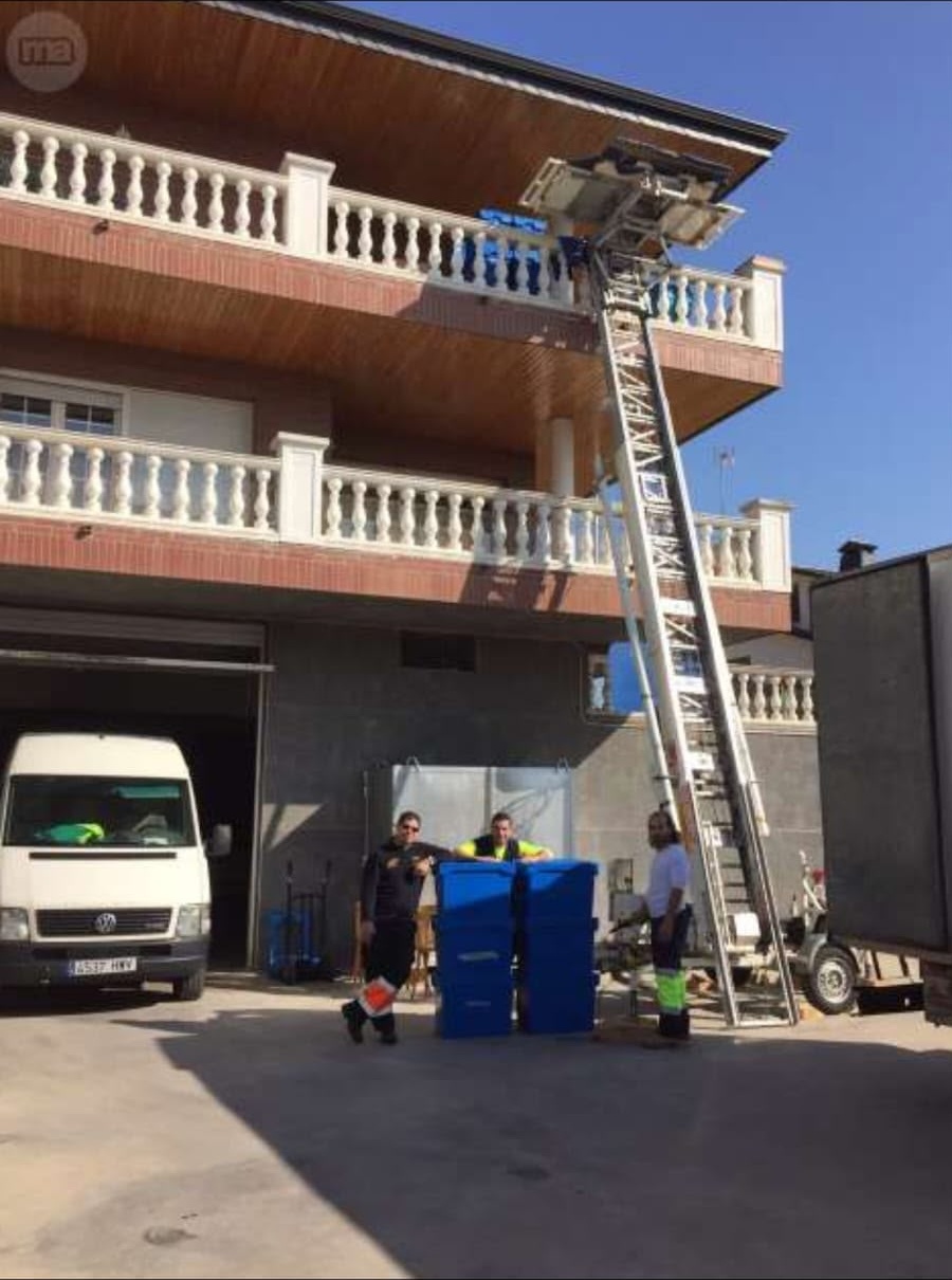 Equipo de mudanzas junto a un elevador apoyado en la terraza de un chalet