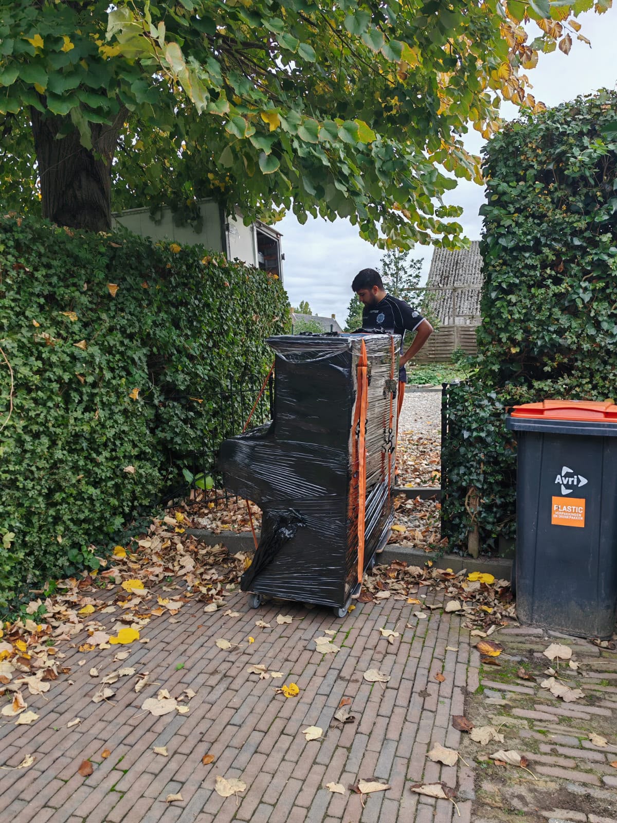 Operario trasladando un piano embalado y sujeto con correas